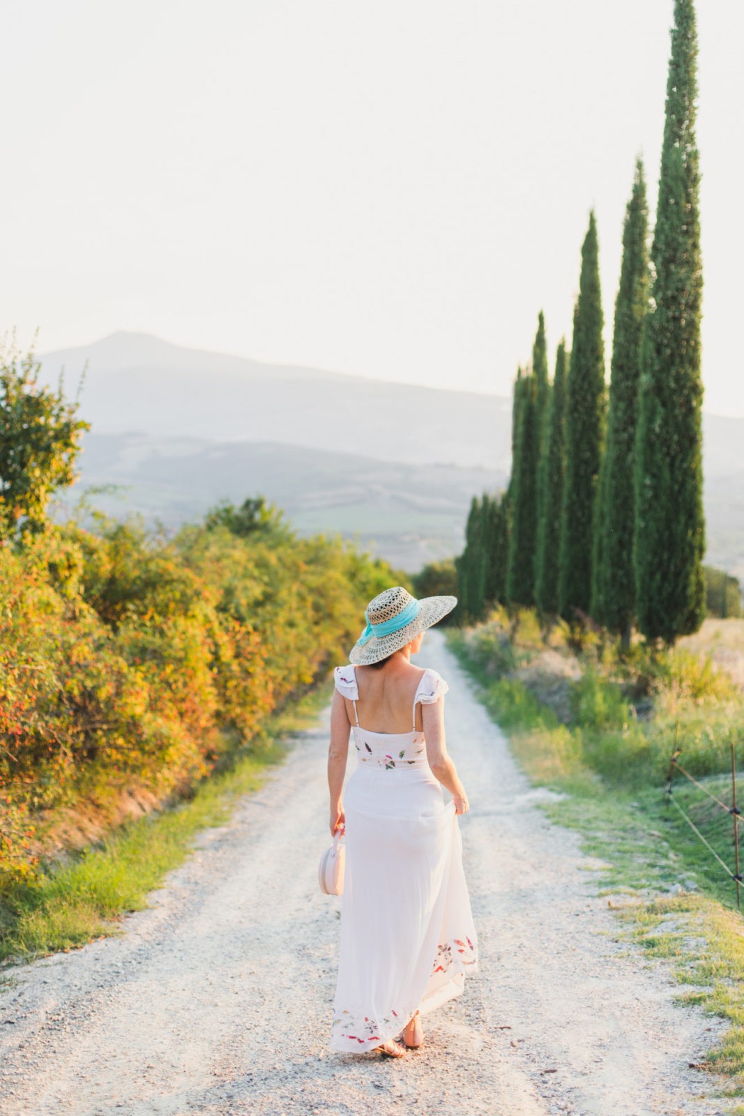 The Tuscan Countryside + Italy Recap by Travel Blogger Laura Lily | How to Take Good Travel Photos by popular California travel blogger, Laura Lily: image of a woman walking down a gravel road in Tuscany, Italy.