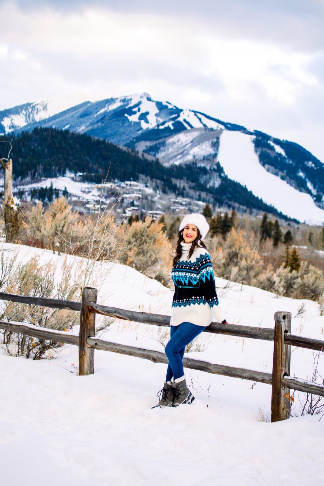 Ski Resort Style featured by top US fashion blogger Laura Lily; Image of a woman wearing Topshop Sweater, Mott & Bow Jeans, Sorel boots, NOAKE hat and Aldo sunglasses.