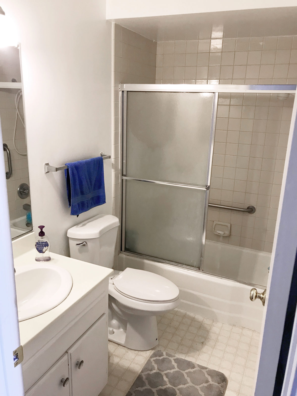 Modern Bathroom Remodel Ideas + Reveal featured by top US lifestyle blogger, Laura Lily: image of before photo of outdated master bathroom with low shower ceiling, linoleum flooring and old vanity.