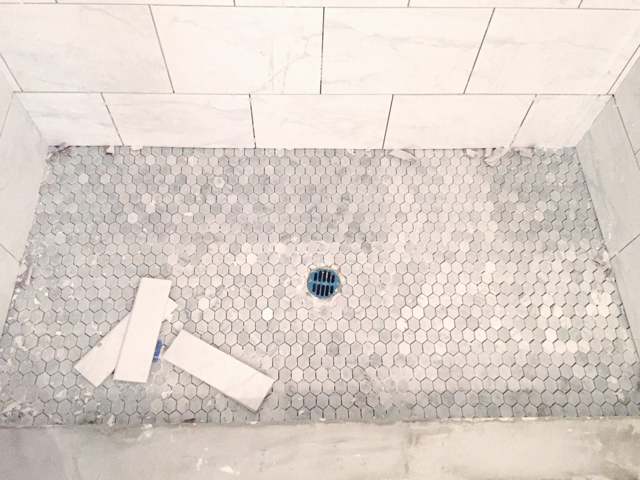 Modern Bathroom Remodel Ideas + Reveal featured by popular US lifestyle blogger, Laura Lily: image of master bathroom shower floor being remodeled with Grey Carrera ceramic mosaic tile.