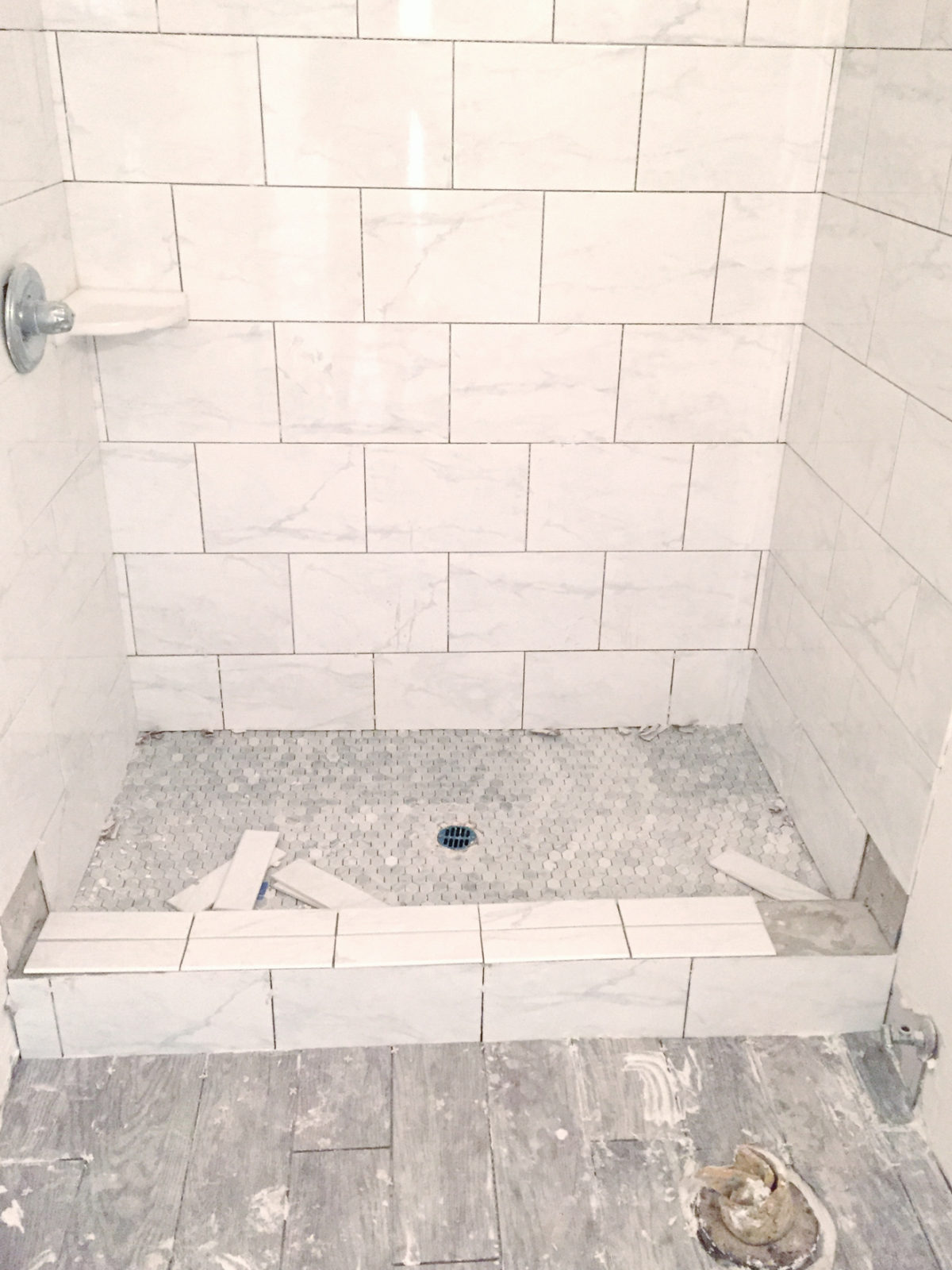Modern Bathroom Remodel Ideas + Reveal featured by top US lifestyle blogger, Laura Lily: image of remodeled shower and dabble grey porcelain tile being laid in master bathroom remodel.