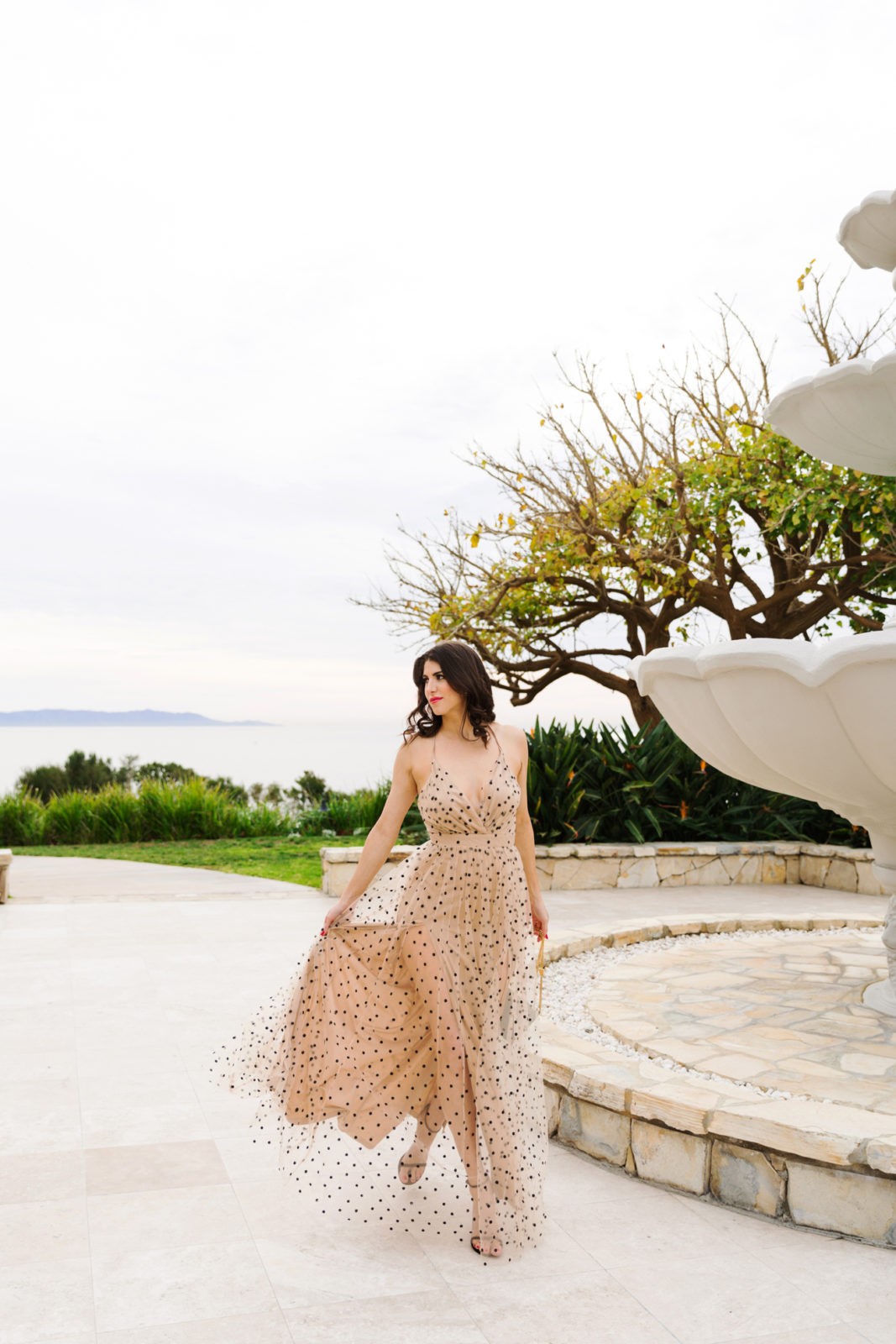 Polka Dot Maxi Dress featured by top US fashion blogger Laura Lily; Image of a woman wearing Red Dress Boutique Nude Polka Dot Maxi Dress, Saint Laurent Handbag and Stuart Weitzman Heels.