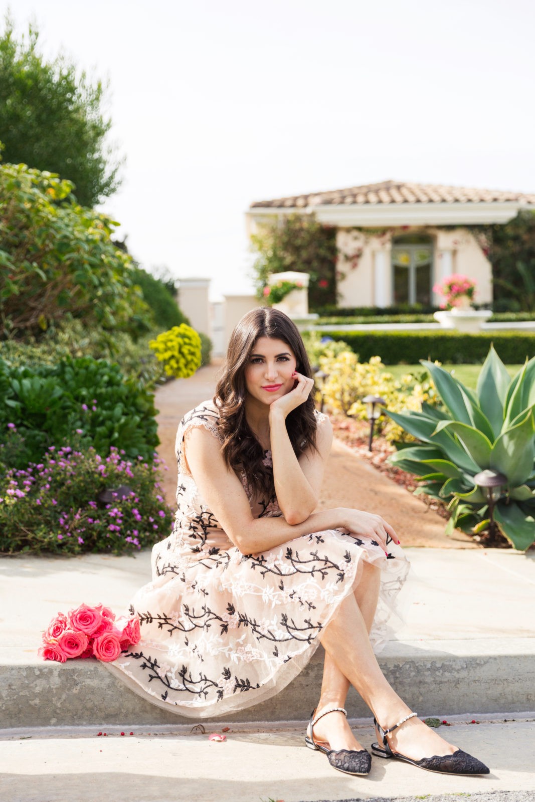 Designer Highlight: Bronx and Banco by popular Los Angeles Fashion Blogger Laura Lily: image of woman wearing Cloe Embroidered mini dress sitting outside next to a pile of pink roses.