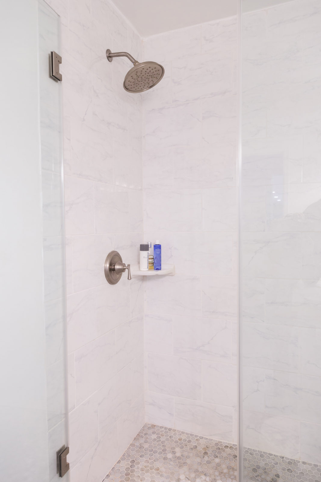 Modern Bathroom Remodel Ideas + Reveal featured by popular US lifestyle blogger, Laura Lily: image of after photo of modern shower remodel with Carrara ceramic wall tile and grey mosaic floor tiles.