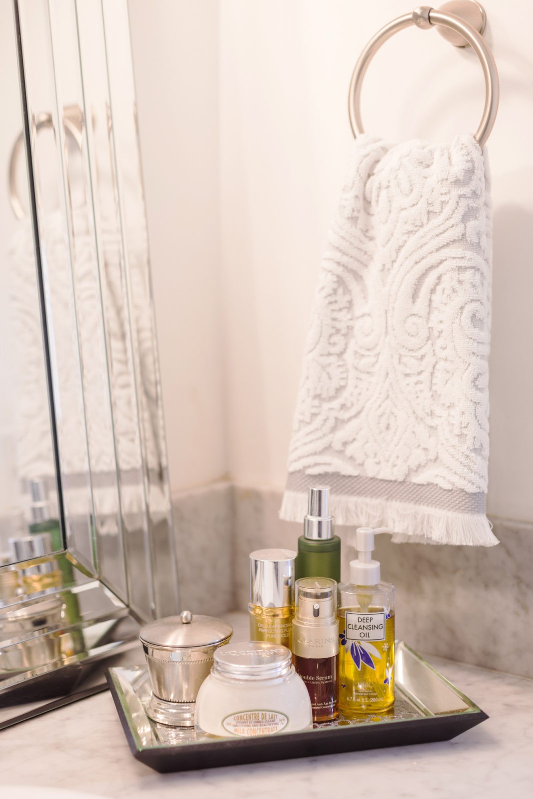 Modern Bathroom Remodel Ideas + Reveal featured by popular US lifestyle blogger, Laura Lily: image of grey damask hand towel and mirrored tray holding body spray, lotion, and face cream.