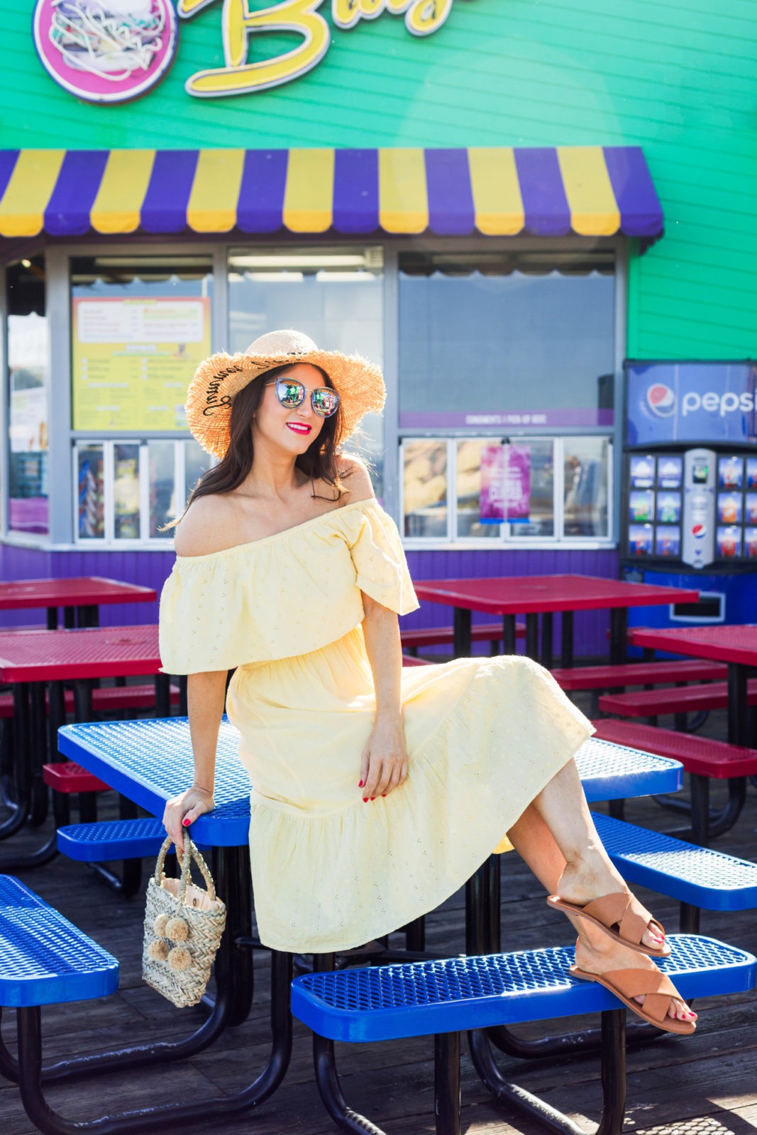 Cute Summer Dresses Under 50, Summer Fashion Trends Walmart We Dress America by popular Los Angeles Fashion Blogger Laura Lily: image of woman wearing  Walmart embroidered straw sun hat, sunglasses, Melrose Ave vegan brown slide sandals, Walmart woven pom handbag, and Walmart off the shoulder light yellow eyelet dress. 