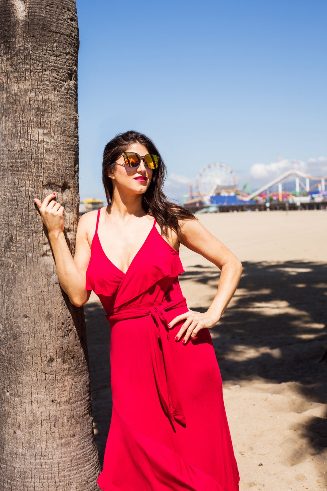 Cute Summer Dresses Under 50, Summer Fashion Trends Walmart We Dress America by popular Los Angeles Fashion Blogger Laura Lily: image of woman at the beach wearing red Walmart faux wrap front maxi dress , Walmart Prive Revaux sunglasses and Eliza May woven blue stripe tote.