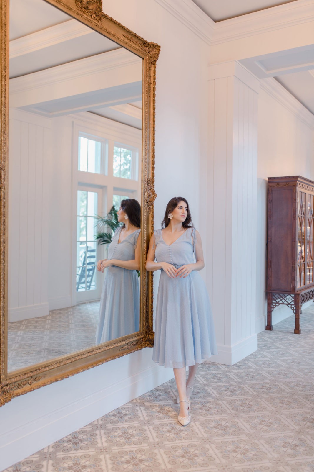 Montage Palmetto Bluff Resort Review by Luxury Travel Blogger Laura Lily: image of a woman in a light blue dress standing next to a large ornate gold framed mirror.