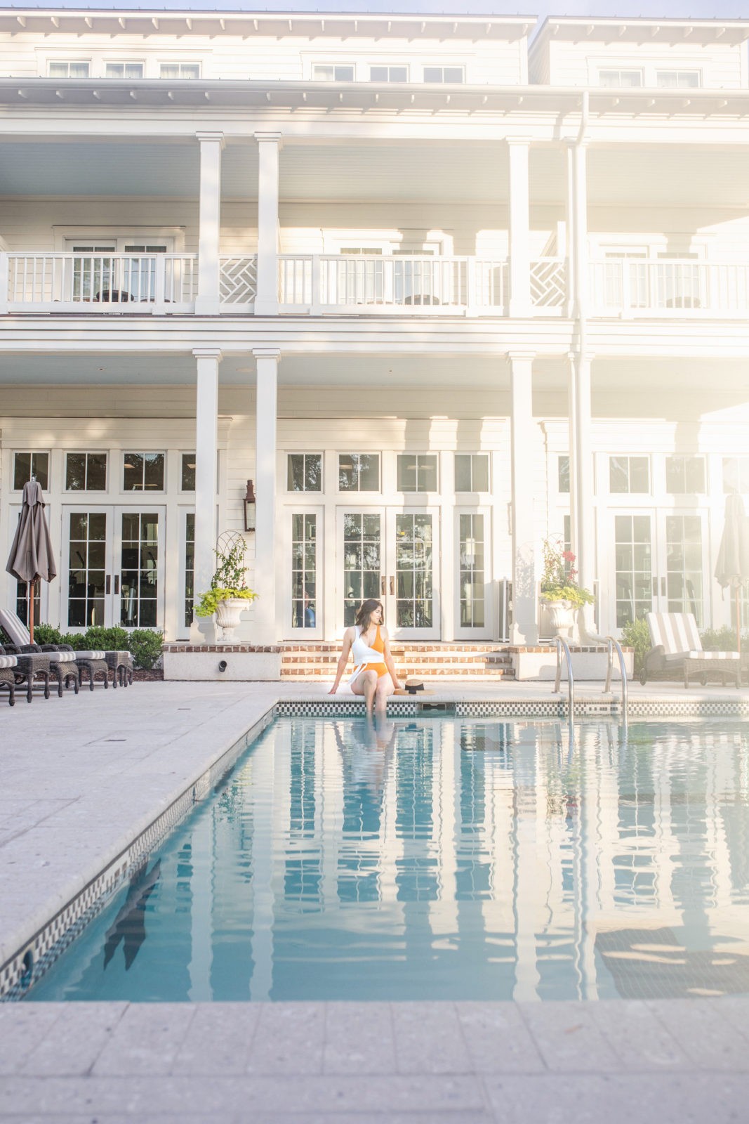 Montage Palmetto Bluff Resort Review by Luxury Travel Blogger Laura Lily: image of a woman sitting on the edge of the pool with her feet in the water.