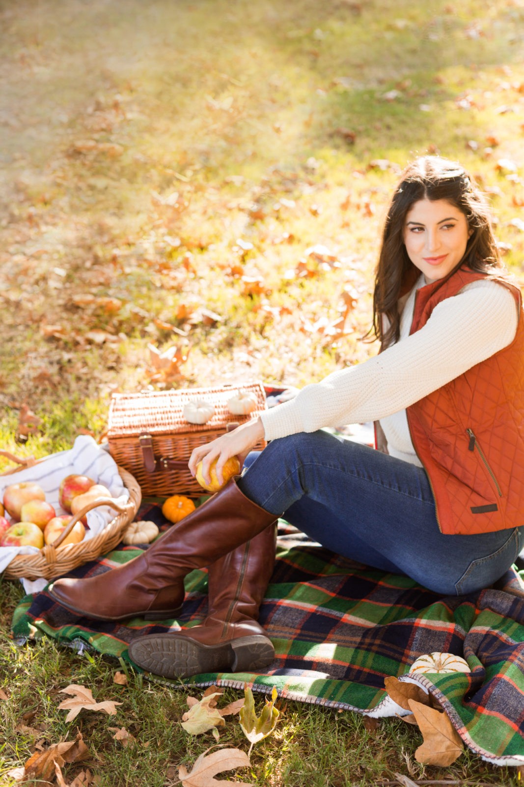 Cozy Fall Favorites by Los Angeles Fashion Blogger Laura Lily | Cozy Fall Fashion Trends by popular California fashion blogger, Laura Lily: image of a woman sitting on a picnic blanket outside and wearing a H&M Chenille Sweater, jeans, Born Boots, and a quilted vest.