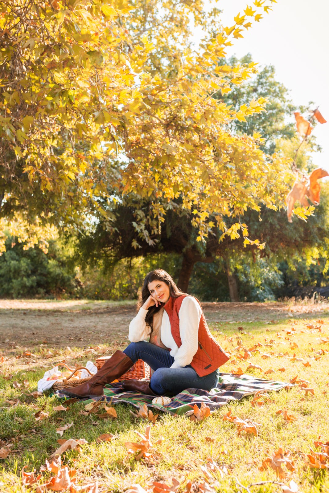 Cozy Fall Favorites by Los Angeles Fashion Blogger Laura Lily | Cozy Fall Fashion Trends by popular California fashion blogger, Laura Lily: image of a woman sitting on a picnic blanket outside and wearing a H&M Chenille Sweater, jeans, Born Boots, and a quilted vest.