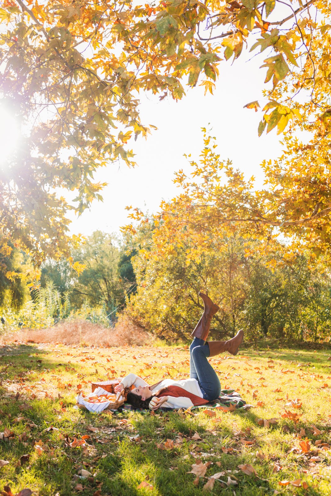 Cozy Fall Favorites by Los Angeles Fashion Blogger Laura Lily | | Cozy Fall Fashion Trends by popular California fashion blogger, Laura Lily: image of a woman laying on a picnic blanket outside and wearing a H&M Chenille Sweater, jeans, Born Boots, and a quilted vest.