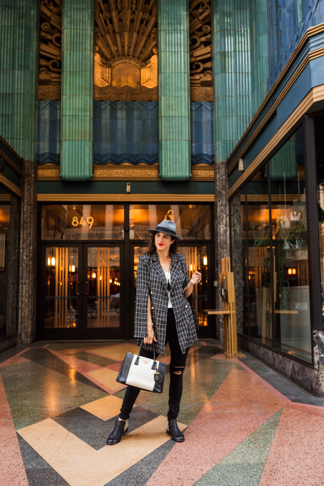 Suburban Girl in an Urban World and my Everyday Fall Outfit by Fashion Blogger Laura Lily, Shein split sleeve blazer, Zappos Naot Helm Bootie, Eastern Building DTLA, | My Everyday Fall Look in the City by popular Los Angeles fashion blogger, Laura Lilly: image of a woman in front of an art deco building and wearing SheIn SHEIN Notch Collar Split Sleeve Double Breasted Grid Blazer, Zappos Naot Helm boot, and Express jeans. 