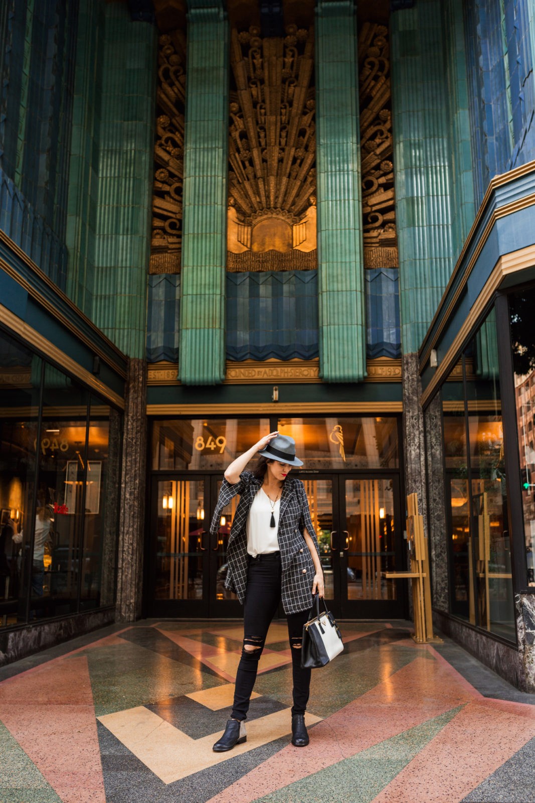 My Everyday Fall Look in the City by popular Los Angeles fashion blogger, Laura Lilly: image of a woman in front of an art deco building and wearing SheIn SHEIN Notch Collar Split Sleeve Double Breasted Grid Blazer, Zappos Naot Helm boot, and Express jeans. 