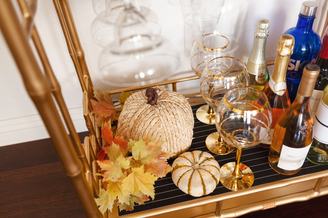Halloween Themed Bar Cart and Party Ideas by Los Angeles Lifestyle Blogger Laura Lily | Halloween Bar Cart Ideas by popular Los Angeles life and style blogger, Laura Lily: image of a Z Gallerie Russo Bar Cart that's decorated with faux pumpkins, faux fall leaves, apothecary jars, wine glasses, and liquor. 
