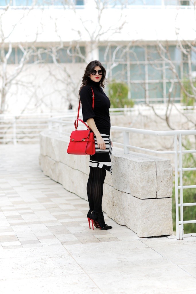 Luxe Fall Work Outfits by Fashion Blogger Laura Lily | Luxe Fall Work Outfits by popular California fashion blogger, Laura Lily: image of a woman wearing a black and white stripe sweater dress and carrying a red bag.