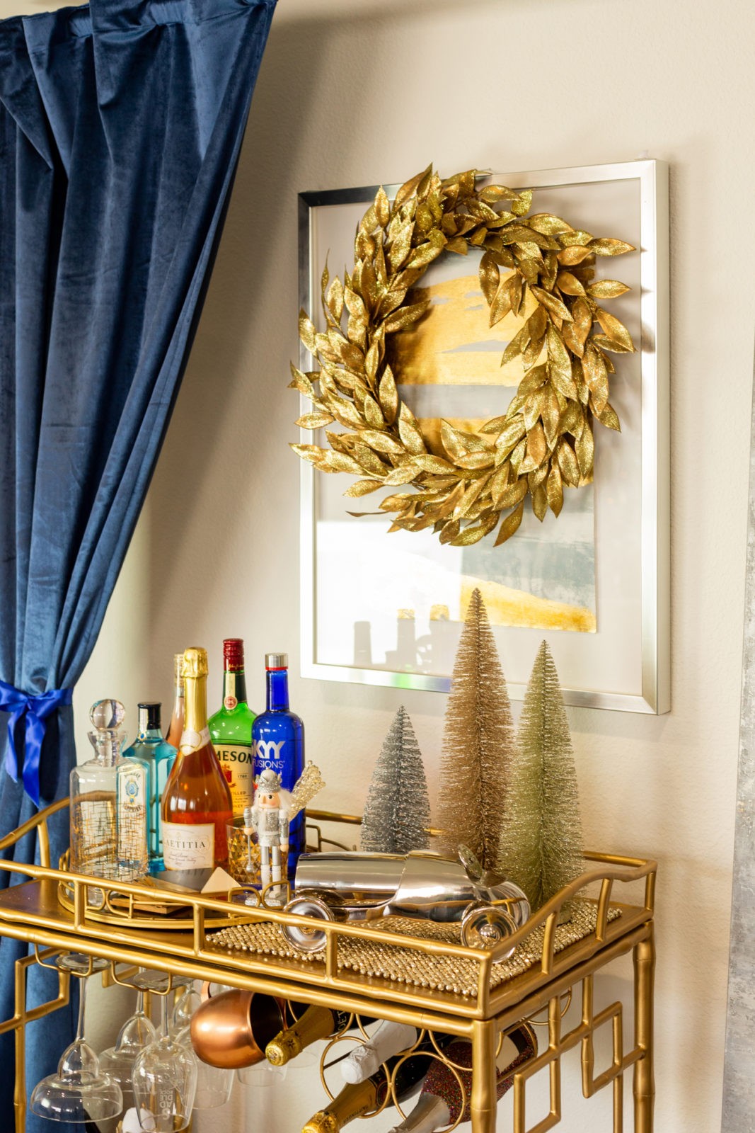 How to Decorate a Holiday Bar Cart in 5 Simple Steps by Home Decor Blogger Laura Lily | How to Decorate a Holiday Bar Cart in 5 Simple Steps by popular Los Angeles life and style blogger, Laura Lily: image of a gold bar cart with various alcoholic drinks, glasses, and holiday decor.
