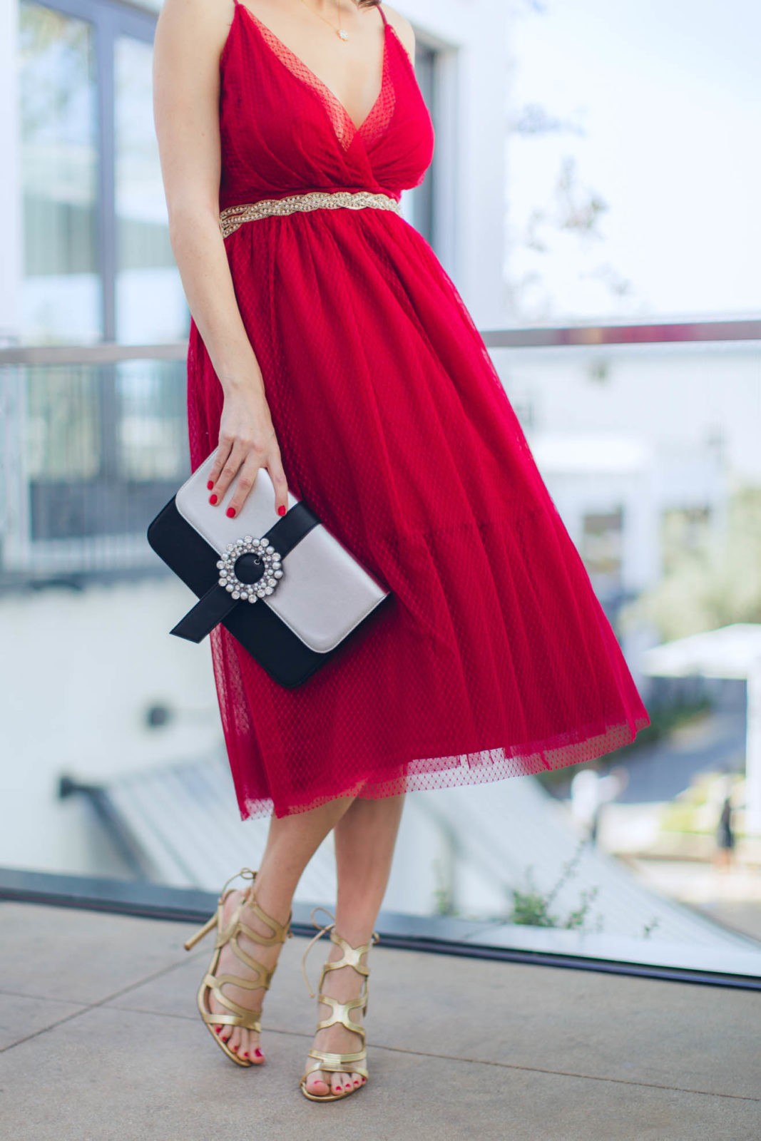 The Ultimate Holiday Outfit Guide by Fashion Blogger Laura Lily, red chiffon dress, New Year's Eve Outfit Ideas | The Ultimate Glam Holiday Outfits Guide by popular Los Angeles fashion blogger, Laura Lily: image of a woman wearing a red tulle dress and gold sandal heels. 