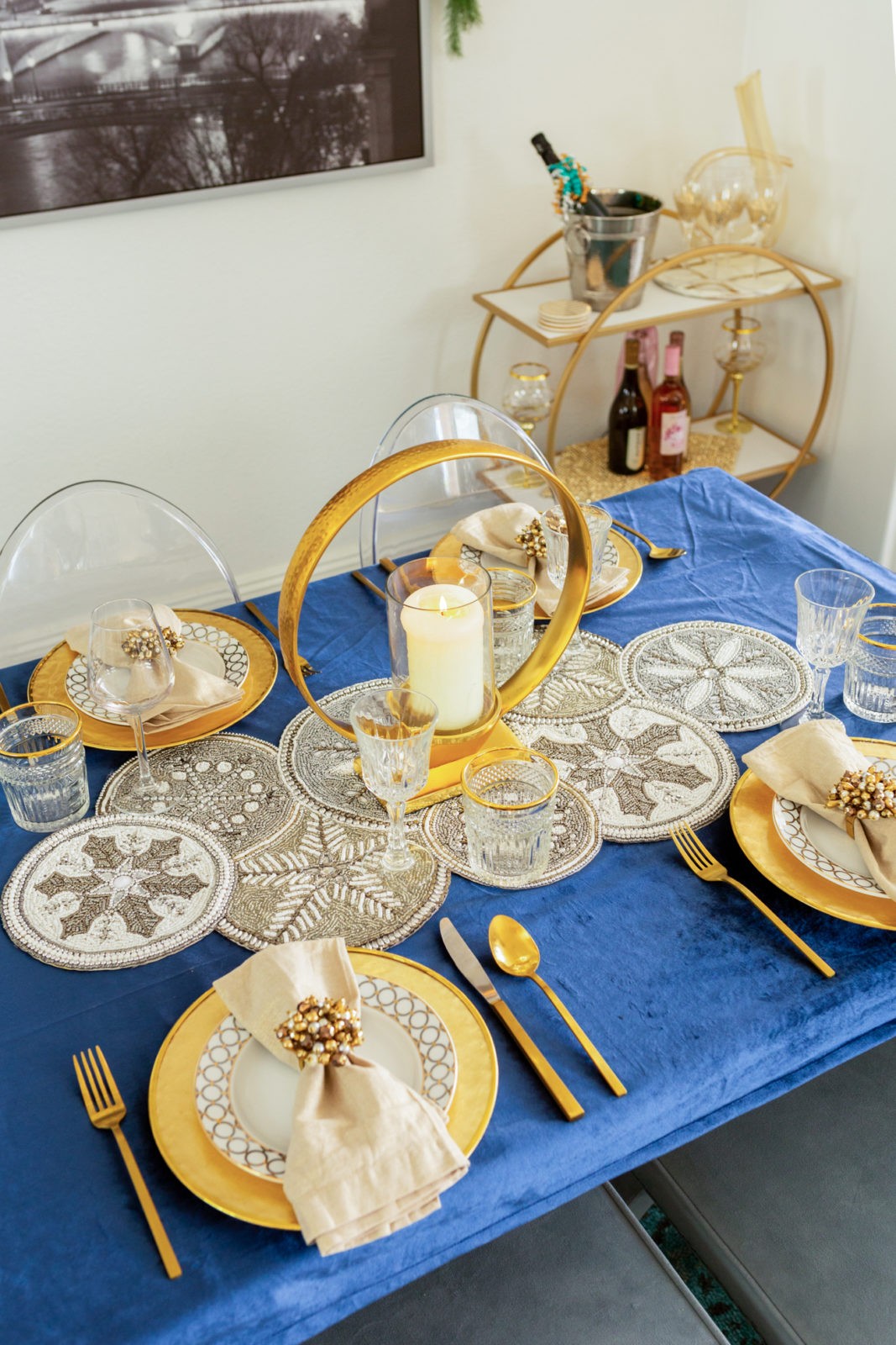 Holiday Home Decor 2019 by popular Los Angeles life and style blogger, Laura Lily: image of a dinning room table decorated with Z Gallierie plates, napkins, and napkin ring holders, Home Goods tablecloth, Amazon silverware, Home Goods beaded table runner, Z Gallerie bar cart, West Elm glasses